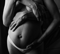 hands hold a pregnancy belly in a black and white image - pregnancy wellbeing services in helsinki by mumfulness.me